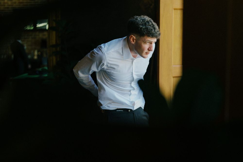 Dramatic side-lit portrait of person in white shirt against dark background.