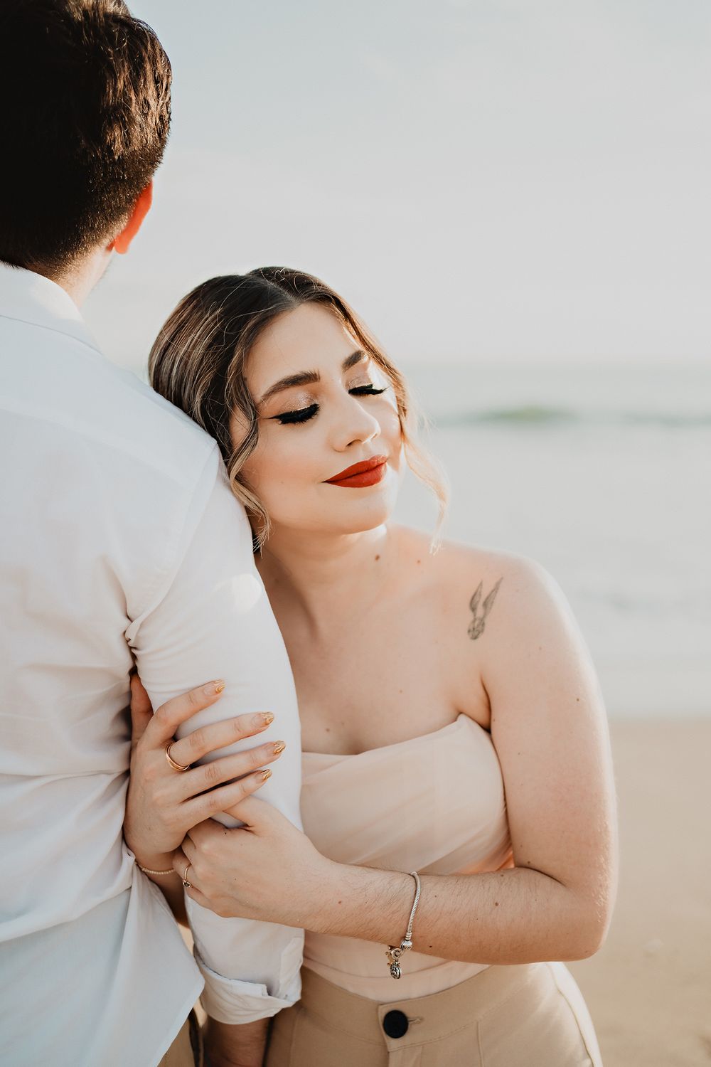 Bride wrapped in her groom's arms, embodying serenity and love during their pre-wedding beach photo shoot
