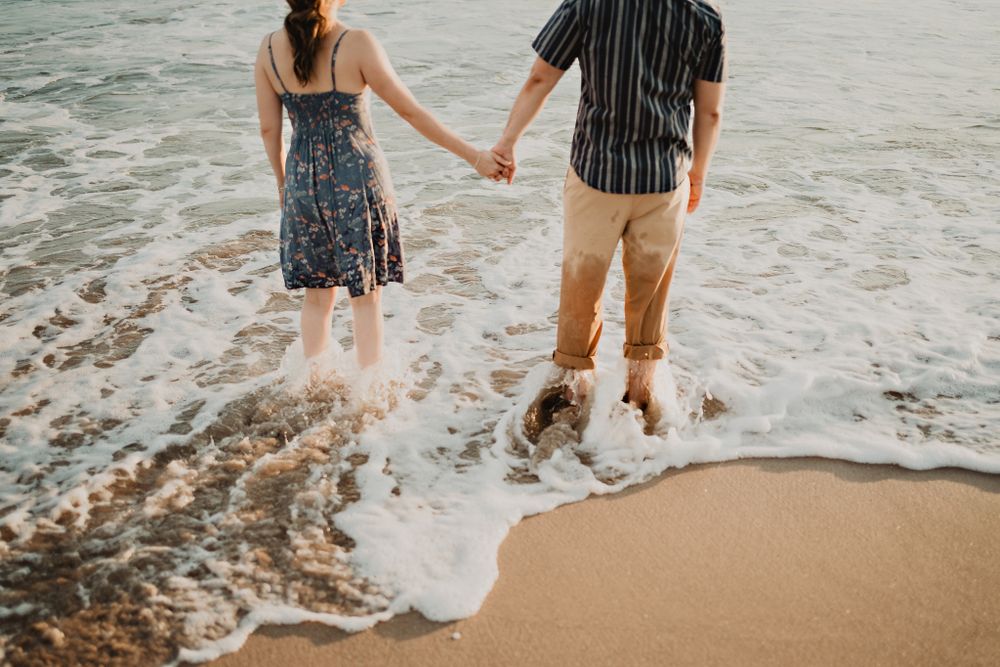 Couple experiencing a wave crashing over them, capturing a joyful moment that reflects their fun-loving spirits