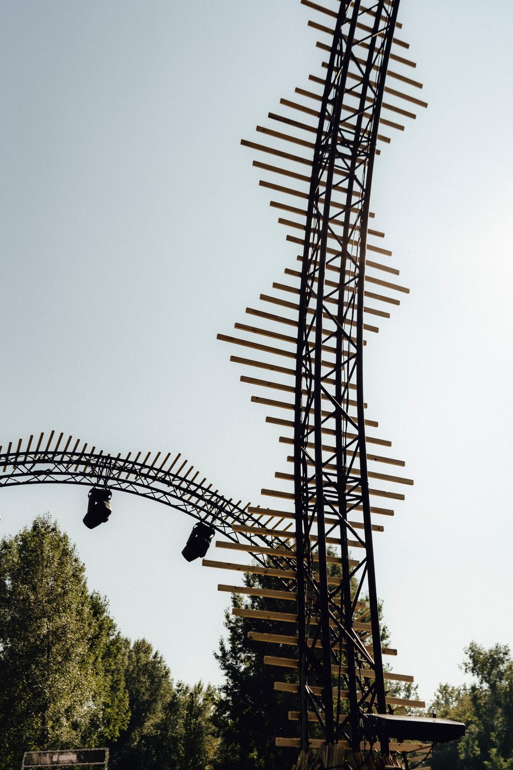 Large sound system speakers and equipment mounted on tall metal truss structures against a bright sky.