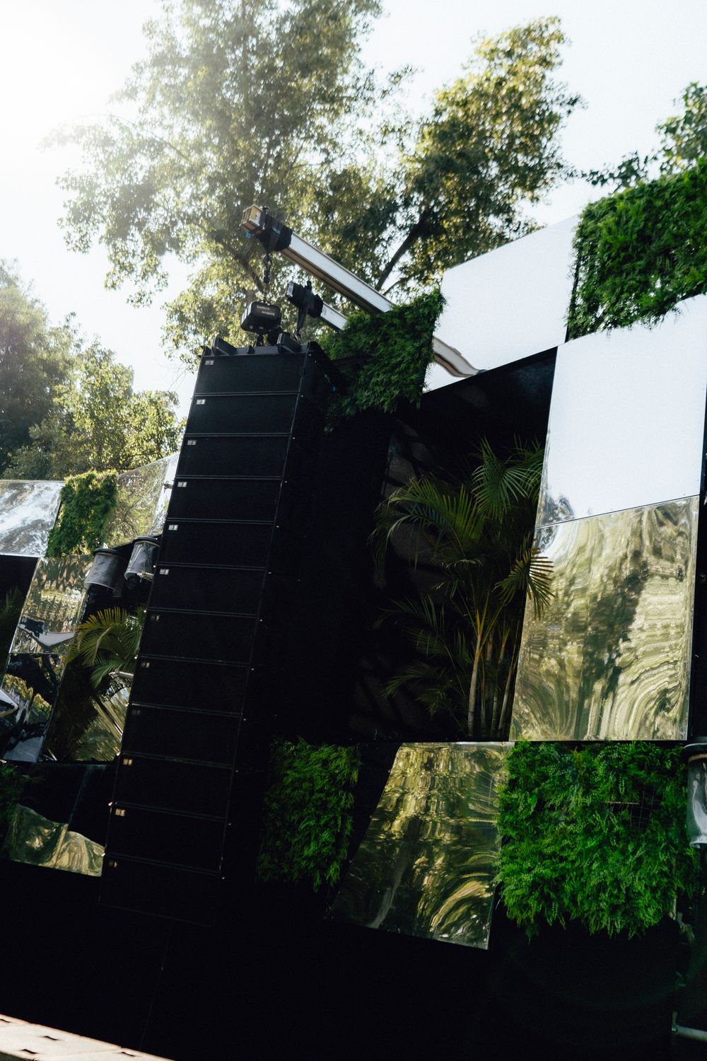 Professional sound system line array speakers mounted in outdoor festival setting with trees in background.