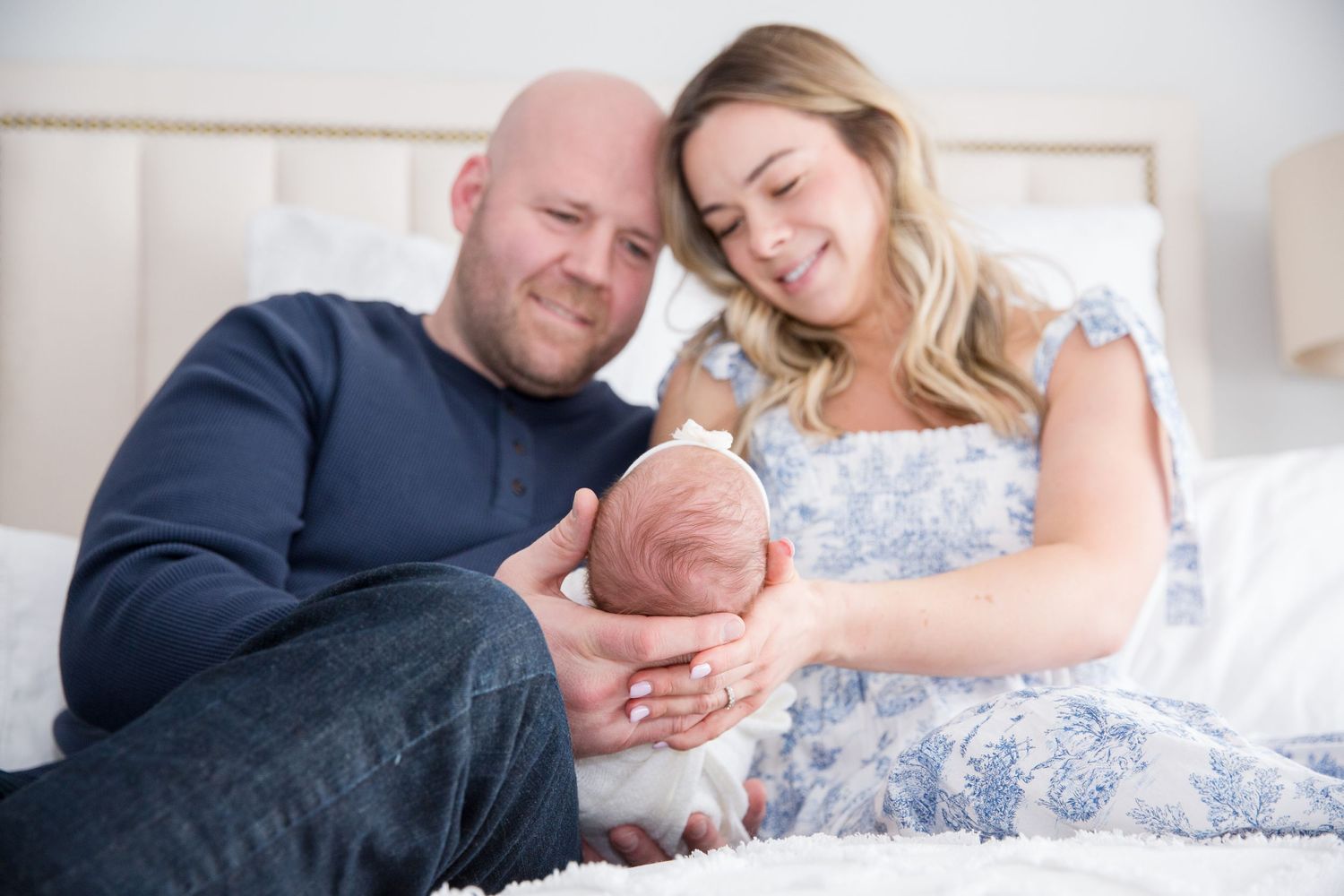 Loving parents snuggle with their newborn baby on a cozy bed.