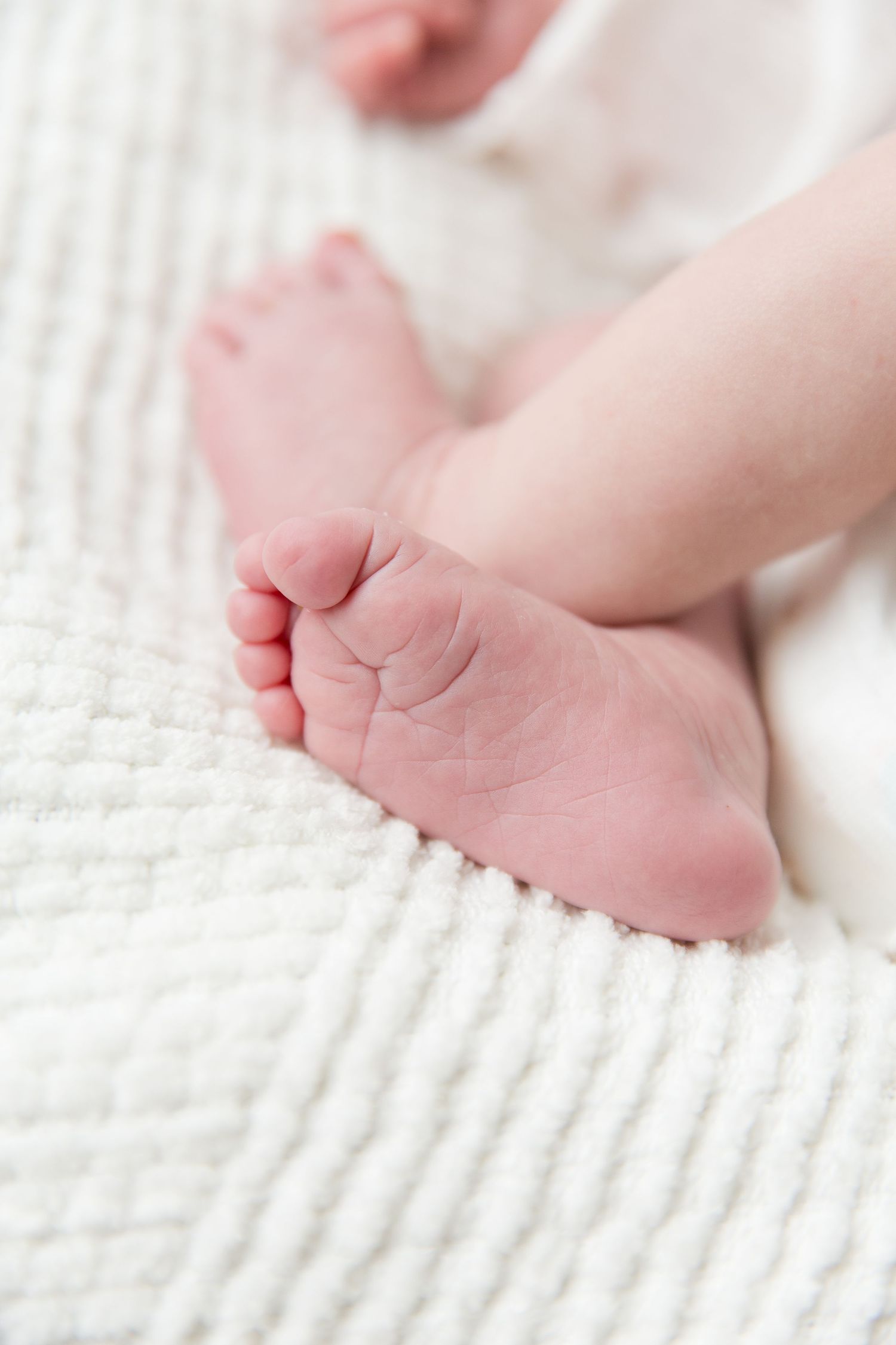 Close-up of tiny baby feet resting on textured white fabric.