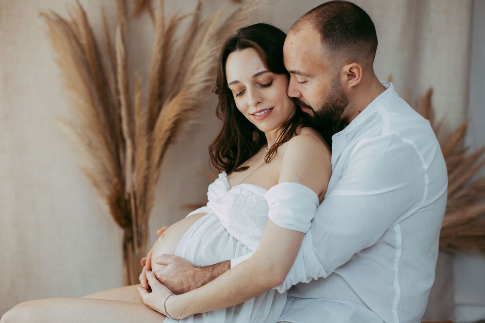 Loving couple embraces tenderly in a romantic photoshoot with soft neutral tones and pampas grass decor.