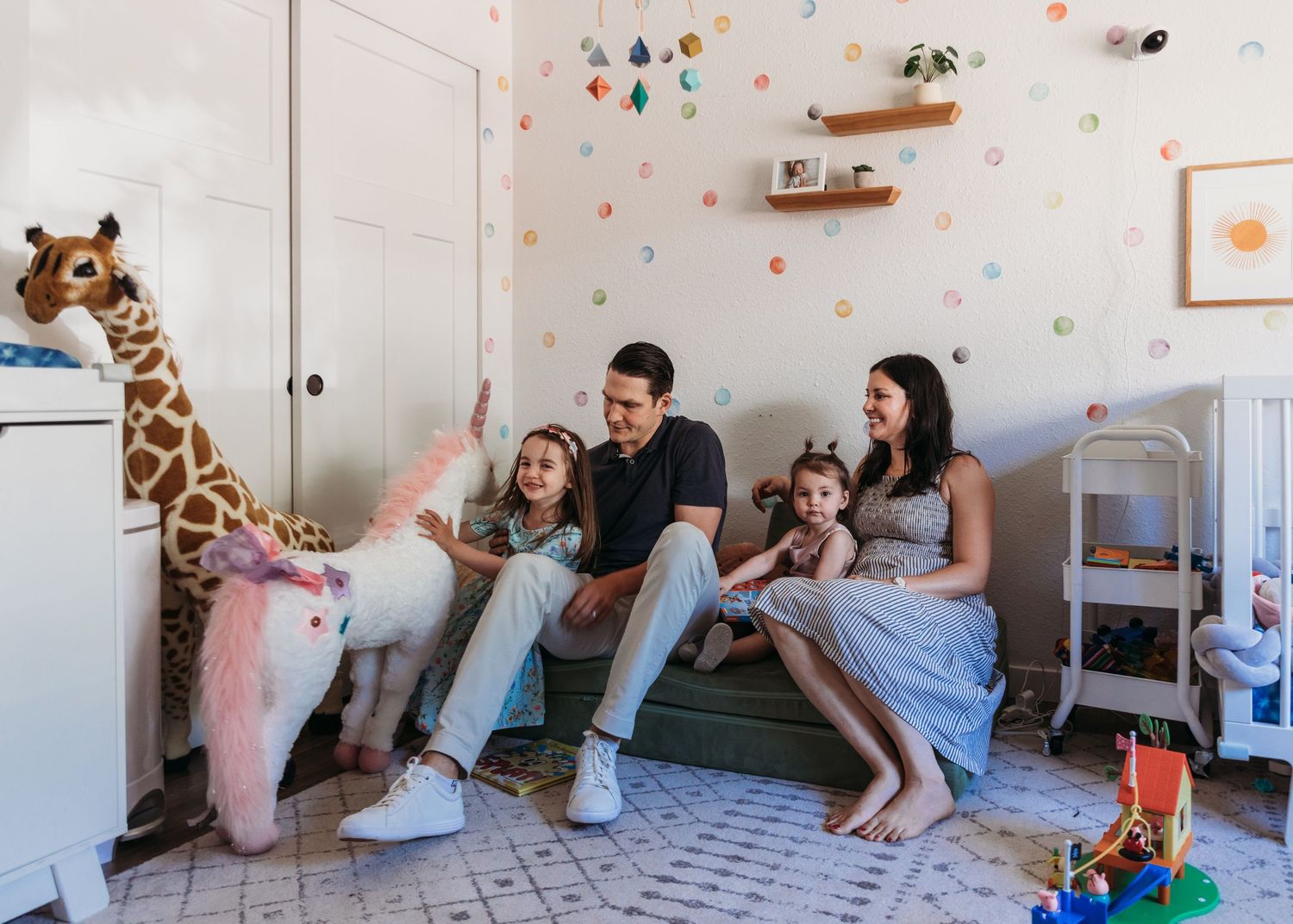 Family relaxing in nursery decorated with giraffe and colorful wall details.