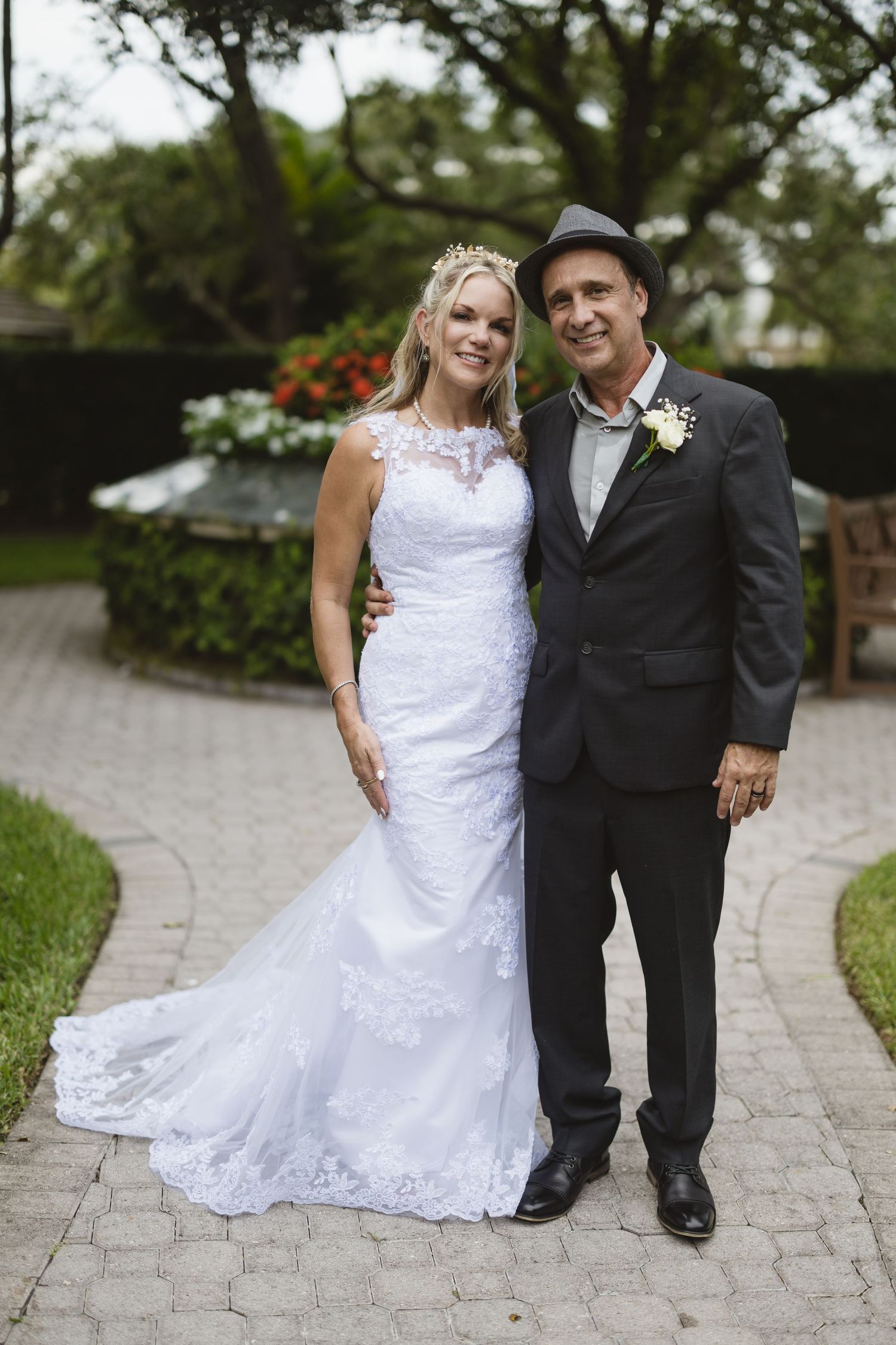 Wedding couple in classic attire standing on a curved garden path.