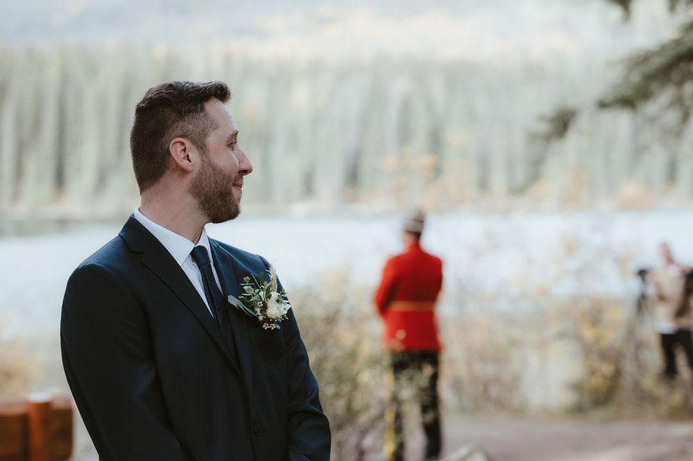 A wedding ceremony takes place against a mountainous backdrop with evergreen trees.