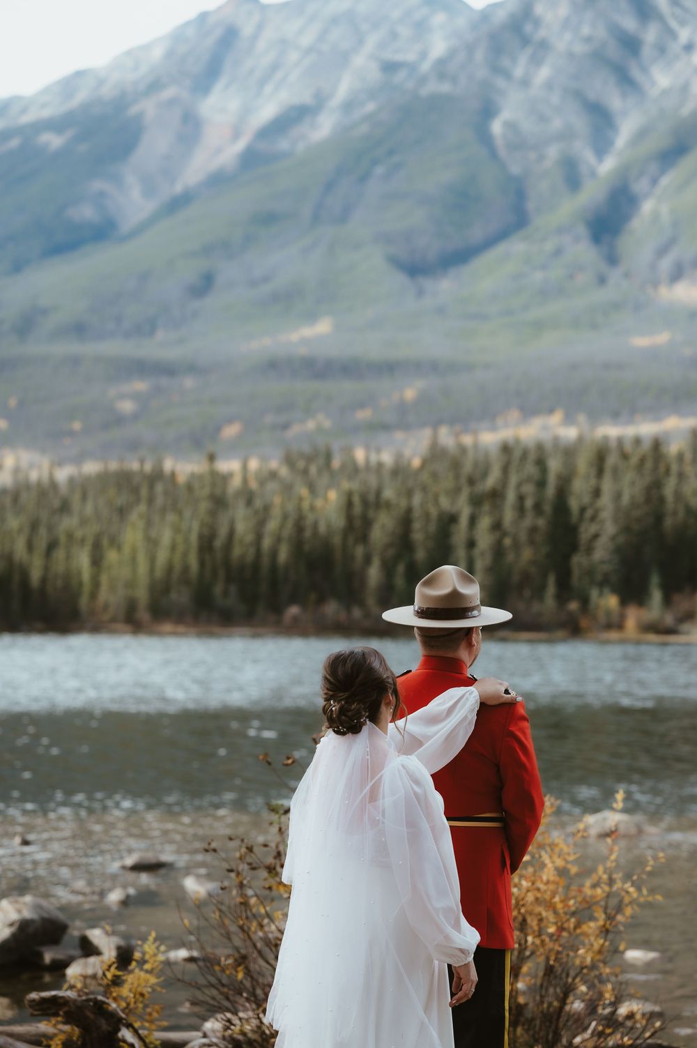 A mountain lake ceremony with a Royal Canadian Mounted Police officer and flowing white dress.