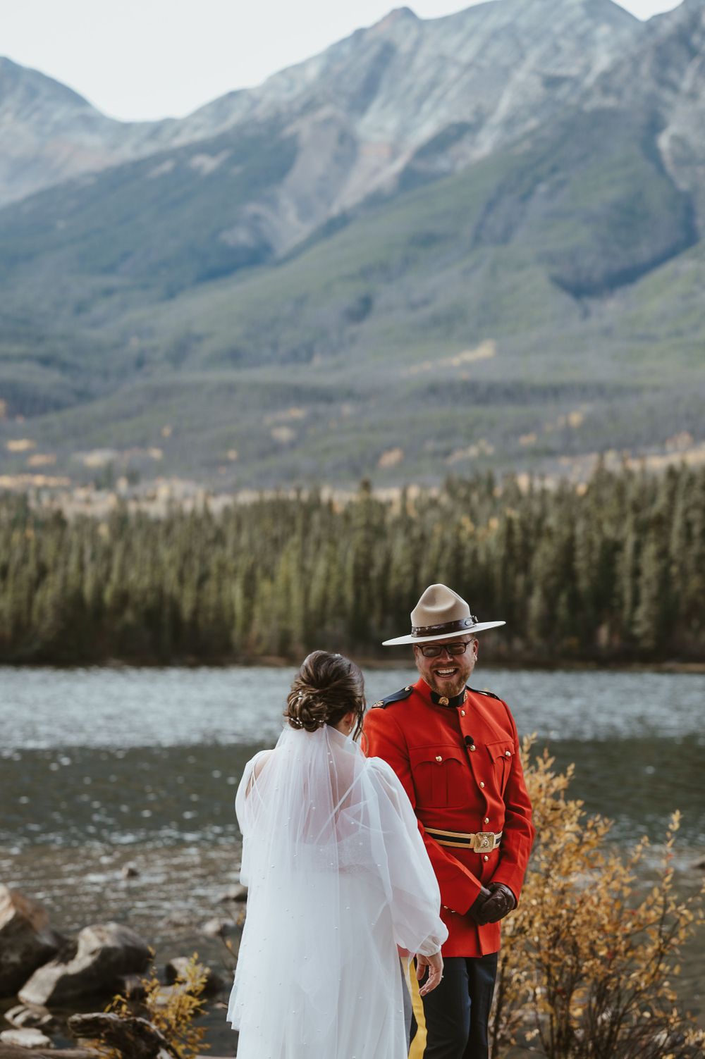 A scenic mountain lake wedding with dramatic peaks and forest in the background.