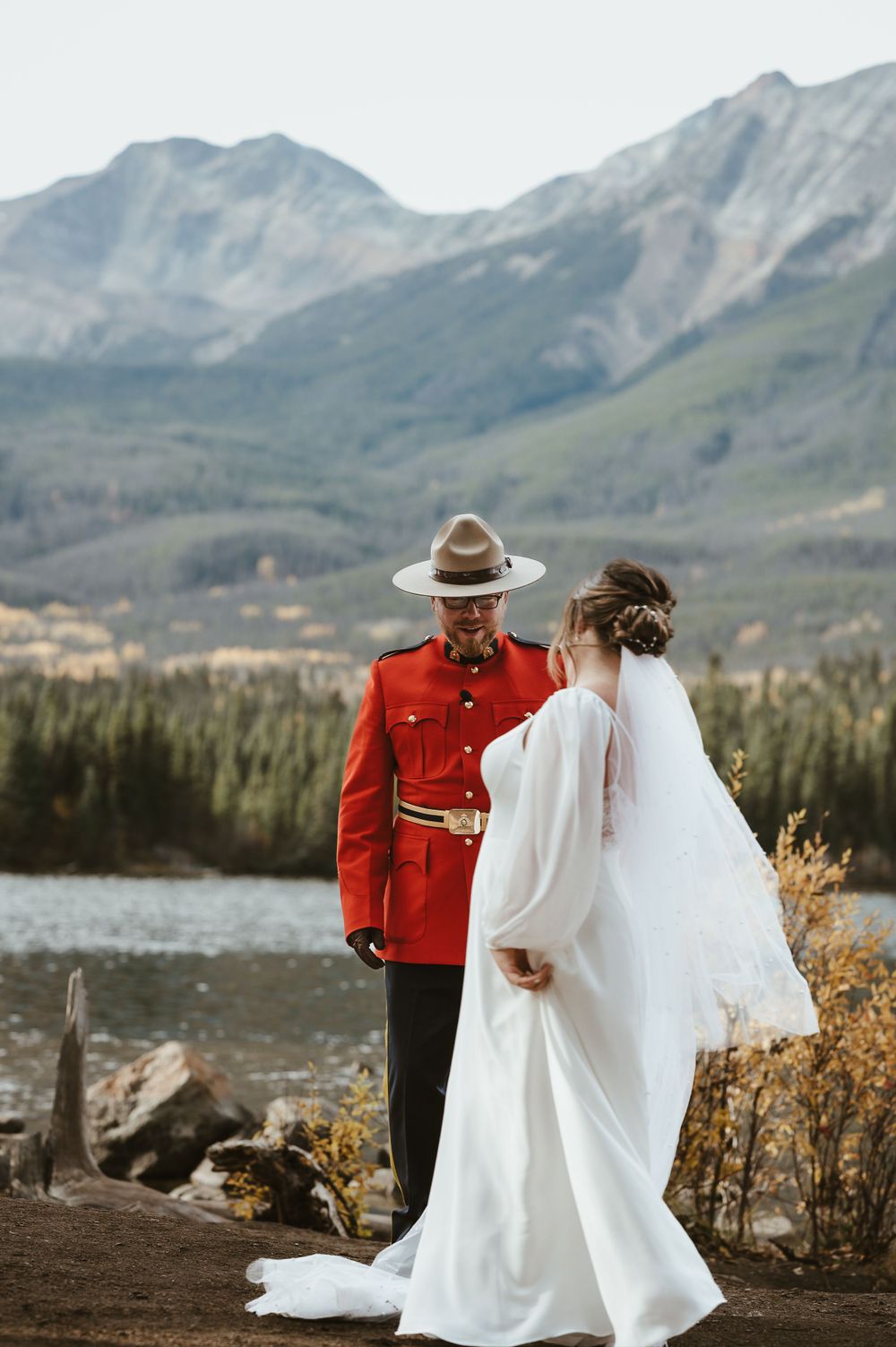A wedding ceremony against a backdrop of mountains and lake with fall foliage in the distance.