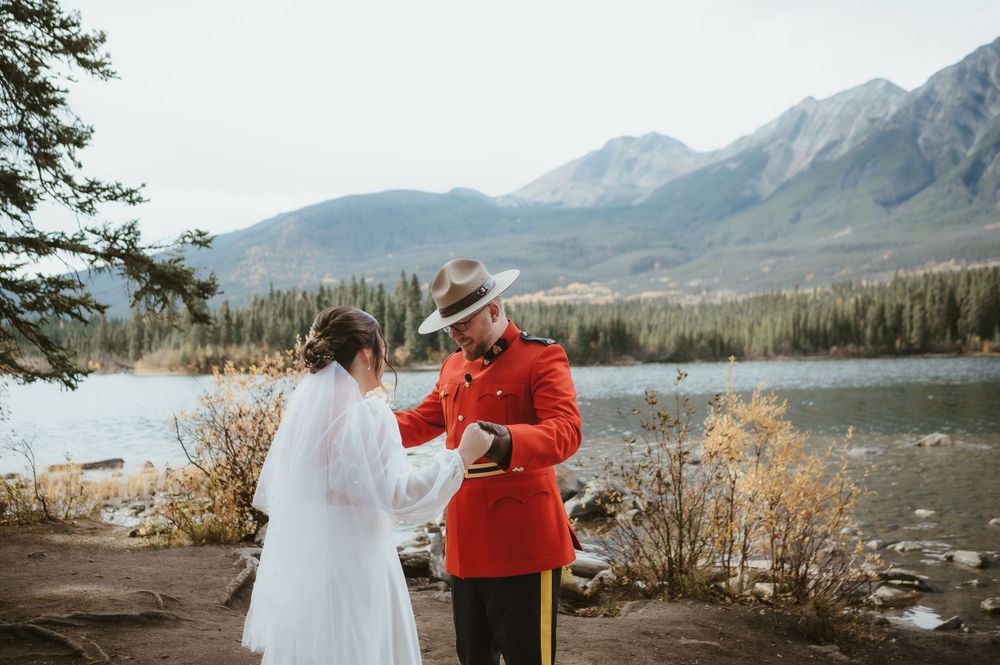 A mountain wedding ceremony taking place on a scenic overlook with snow-capped peaks in the distance.