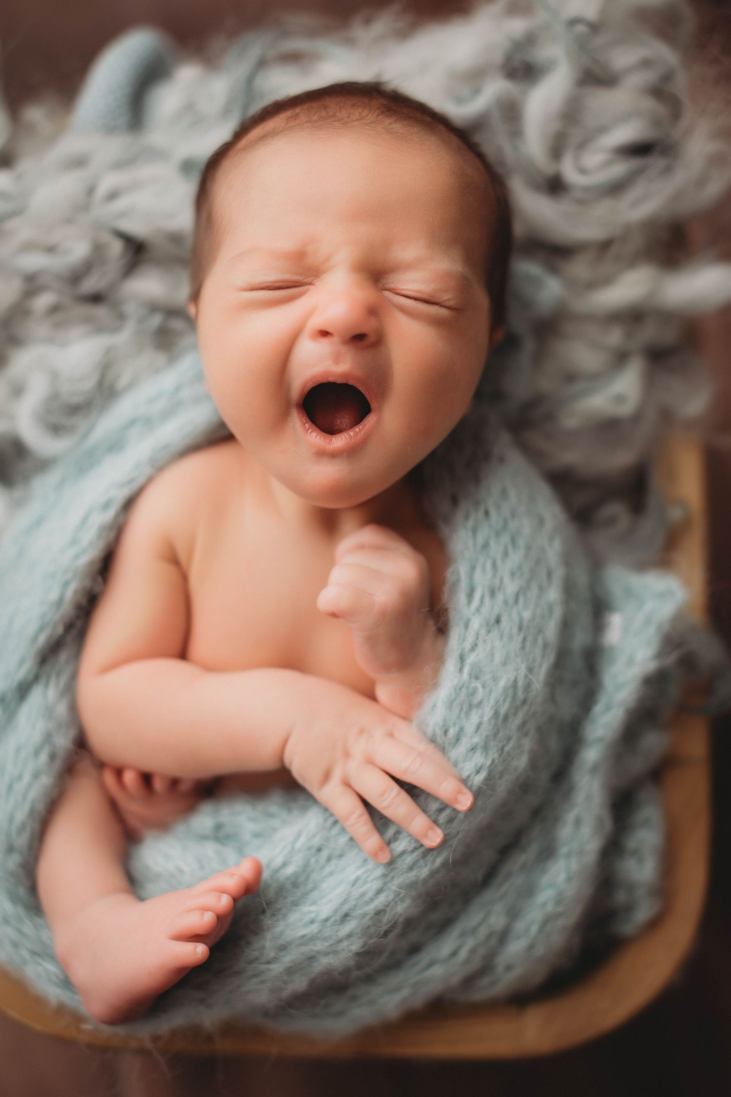 Sleeping newborn wrapped in white swaddle with delicate headband.