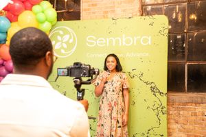Behind-the-scenes video production setup with colorful balloon backdrop and Sembra branding.