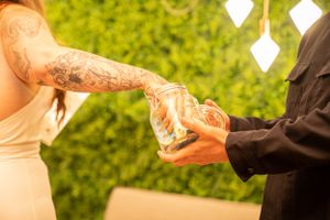 Close-up of tattooed arms pouring drinks during an outdoor event.