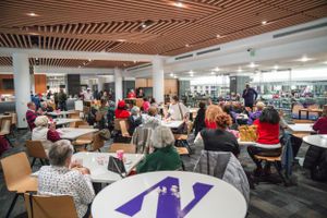 Students gather in a university dining area with Northwestern University branded tables and wooden ceiling panels.