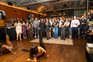 A vibrant dance party scene with people dancing on a wooden floor under ambient lighting.
