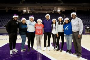 A group wearing winter hats poses together on a purple basketball court.