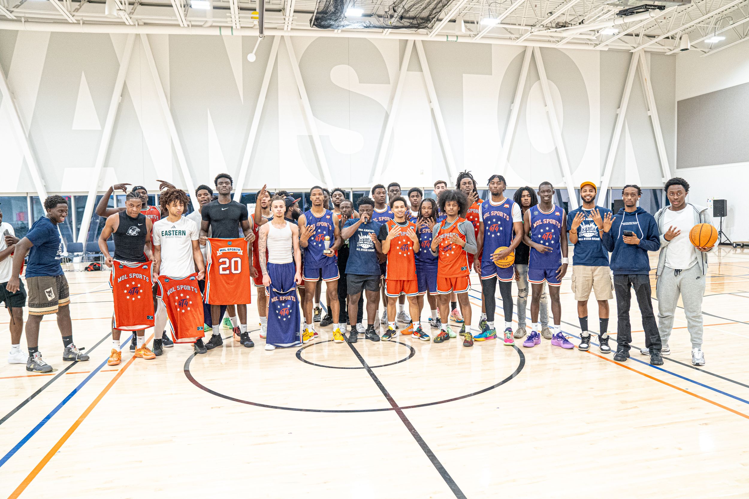Basketball players and coaches gather for a group photo on a court with WASATCH branding visible.