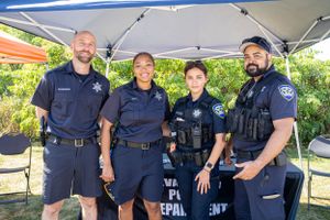 Public safety officers stand together under a tent at a community outreach event.