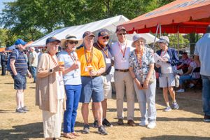 Seniors gather under red umbrellas at an outdoor community event.