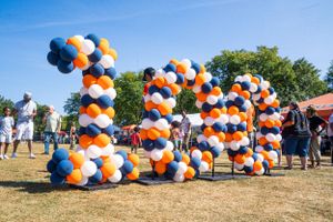 Orange and blue balloon arch display at an outdoor festival.