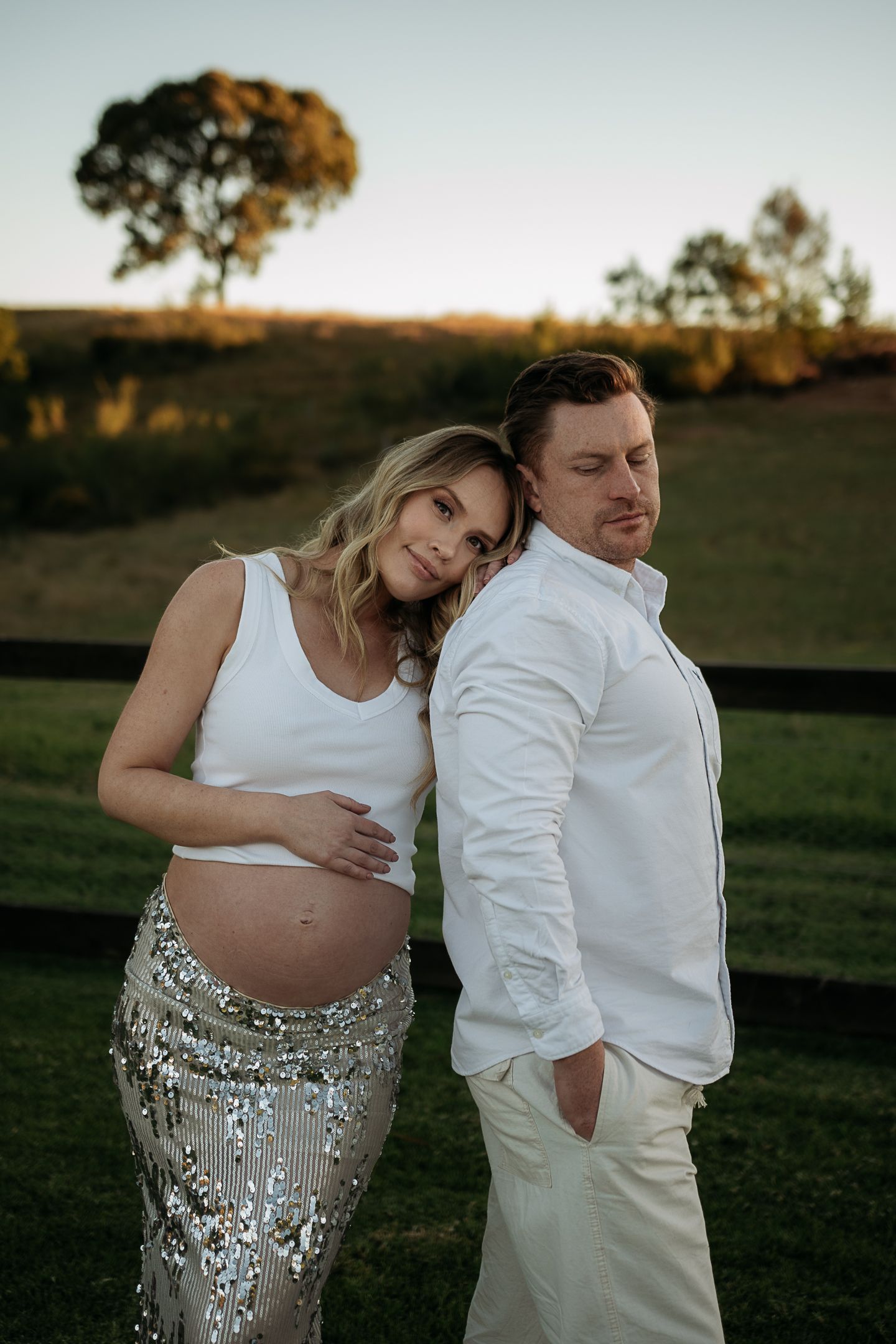 Couple at sunset looking at camera with baby bump taken at Western Sydney Location