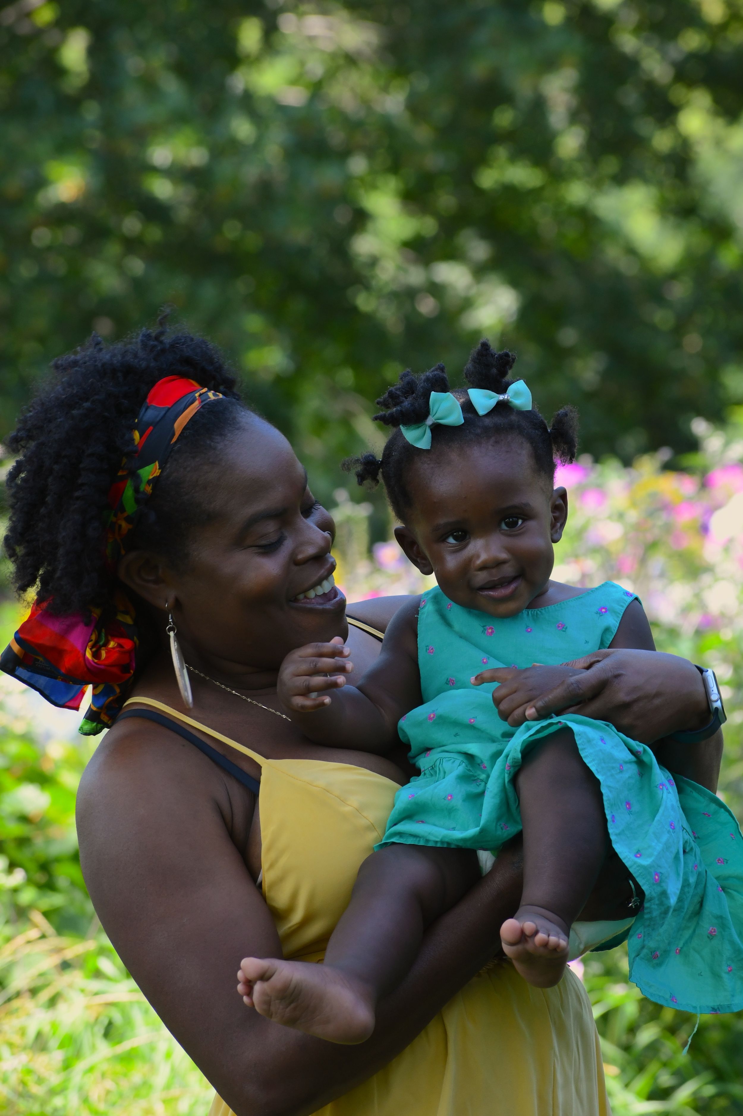 A joyful moment captured outdoors shows two people sharing smiles and laughter in a garden setting with green foliage.