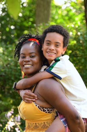 A loving family moment captured outdoors with warm smiles and a green natural backdrop on a sunny day.