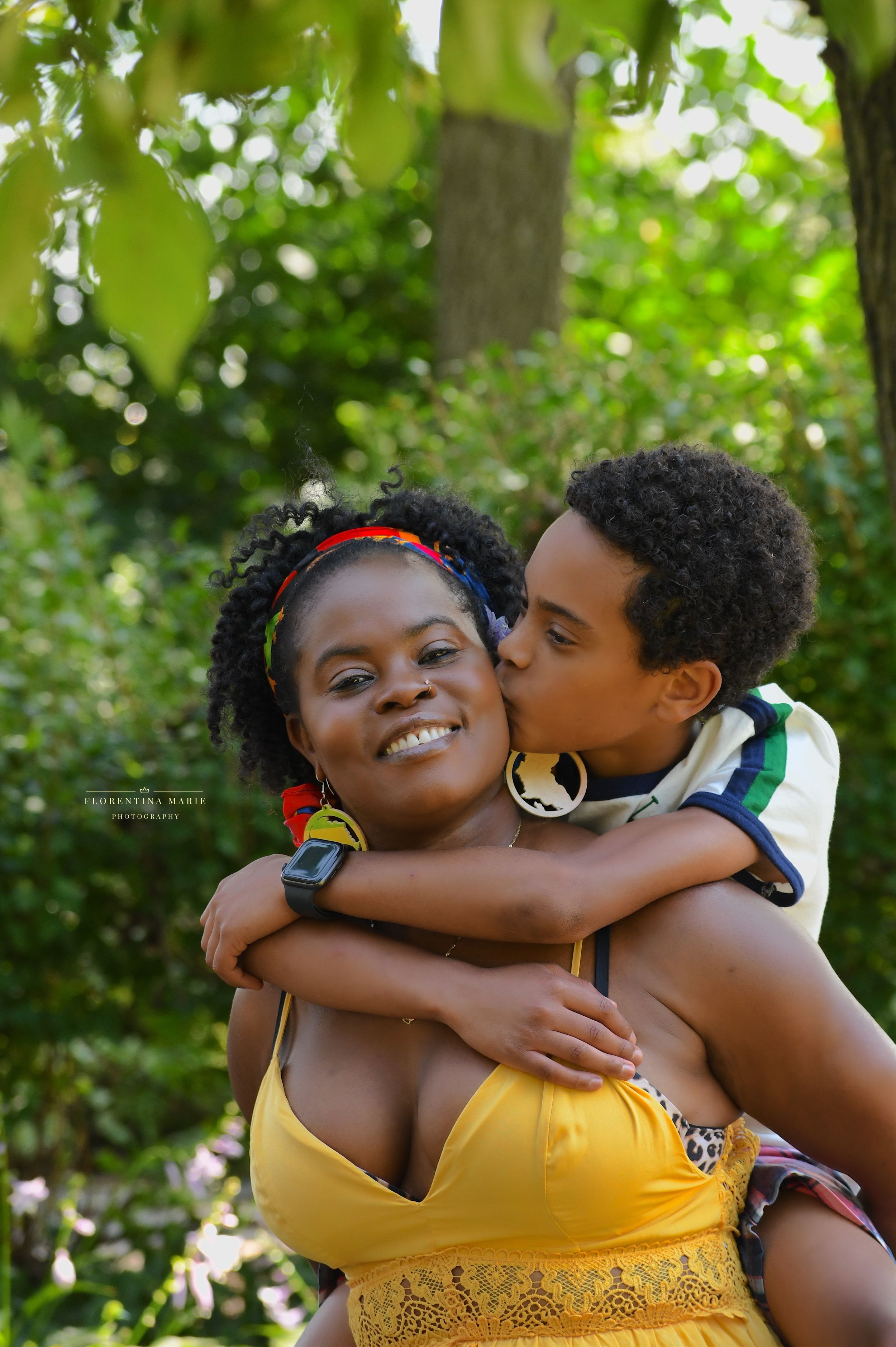A tender embrace shared between two people outdoors in a natural setting with lush green foliage in the background.