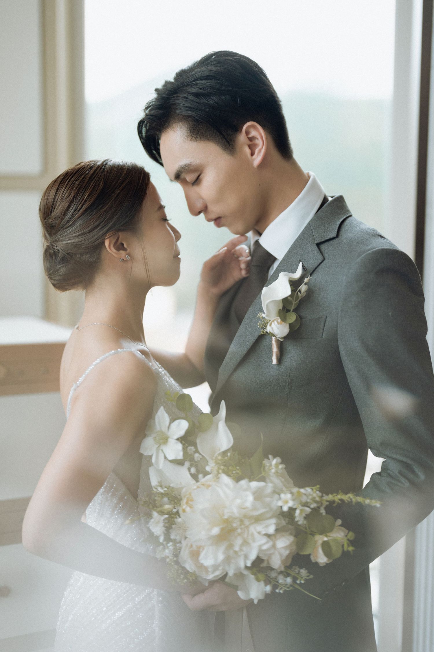 A romantic wedding portrait showing a tender moment with white floral decorations.
