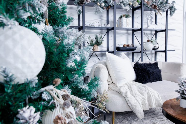 Modern Christmas decor featuring a white chair, tree, and industrial shelving in a contemporary space.