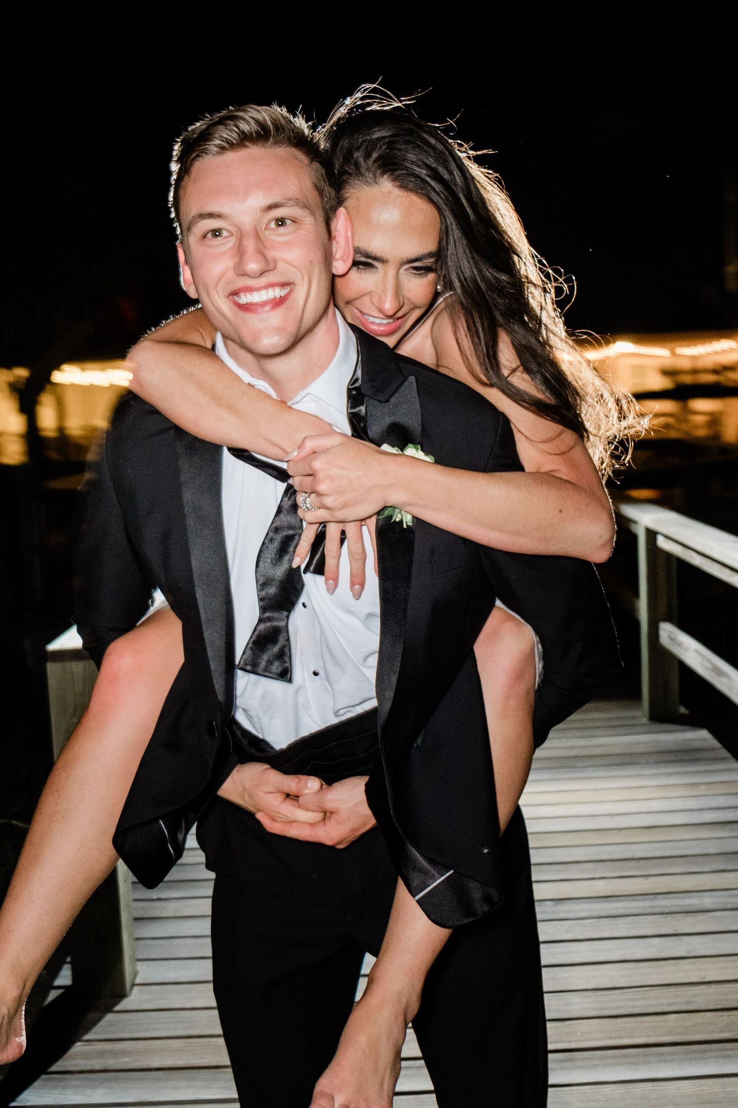 A joyful piggyback ride moment at night with a couple in formal attire.