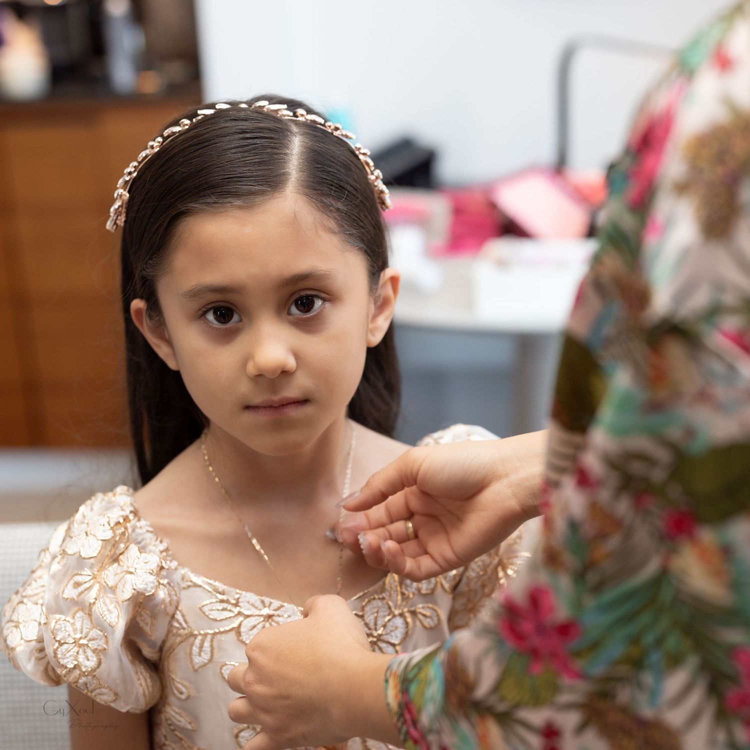 A young person wears a delicate lace dress while getting ready for a formal occasion.