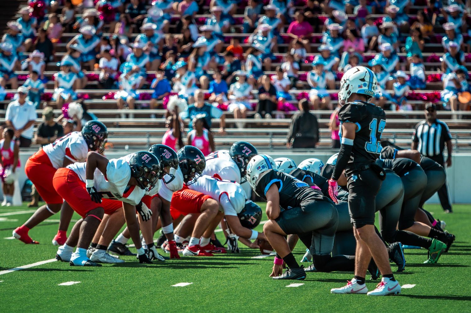 Two football teams line up in formation at the line of scrimmage during a game.