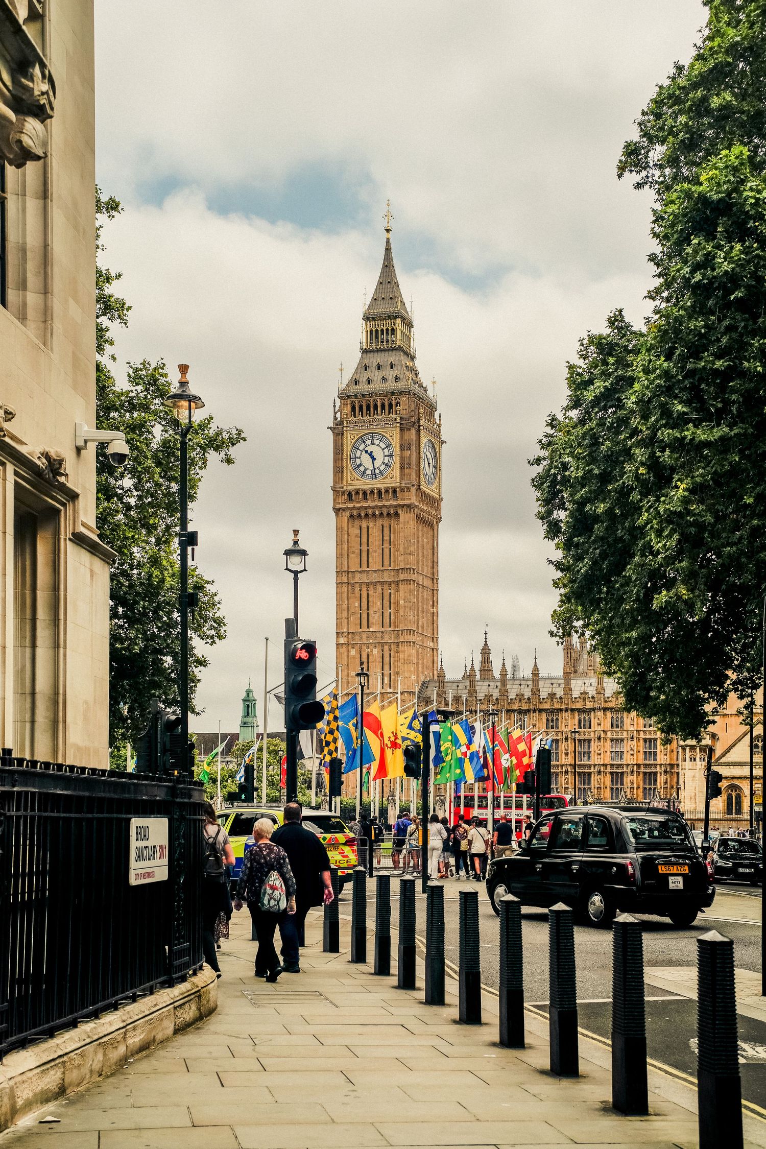 Big Ben and Houses of Parliament with colorful flags flying along Westminster street.