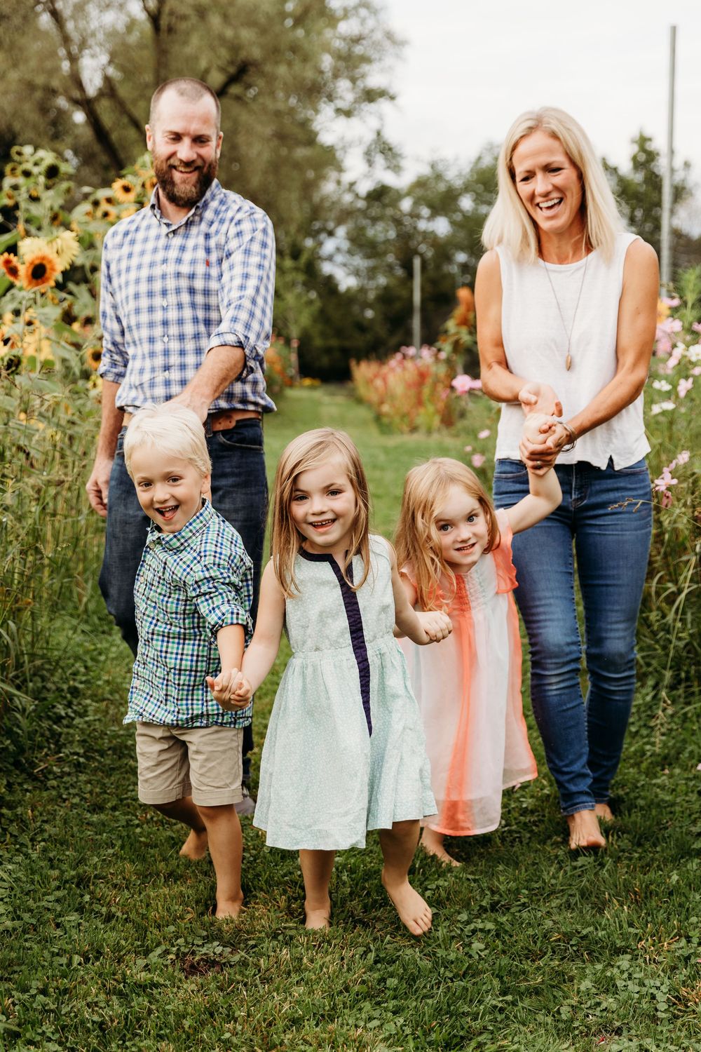 Family photo session in a beautiful garden with blooming flowers and greenery.