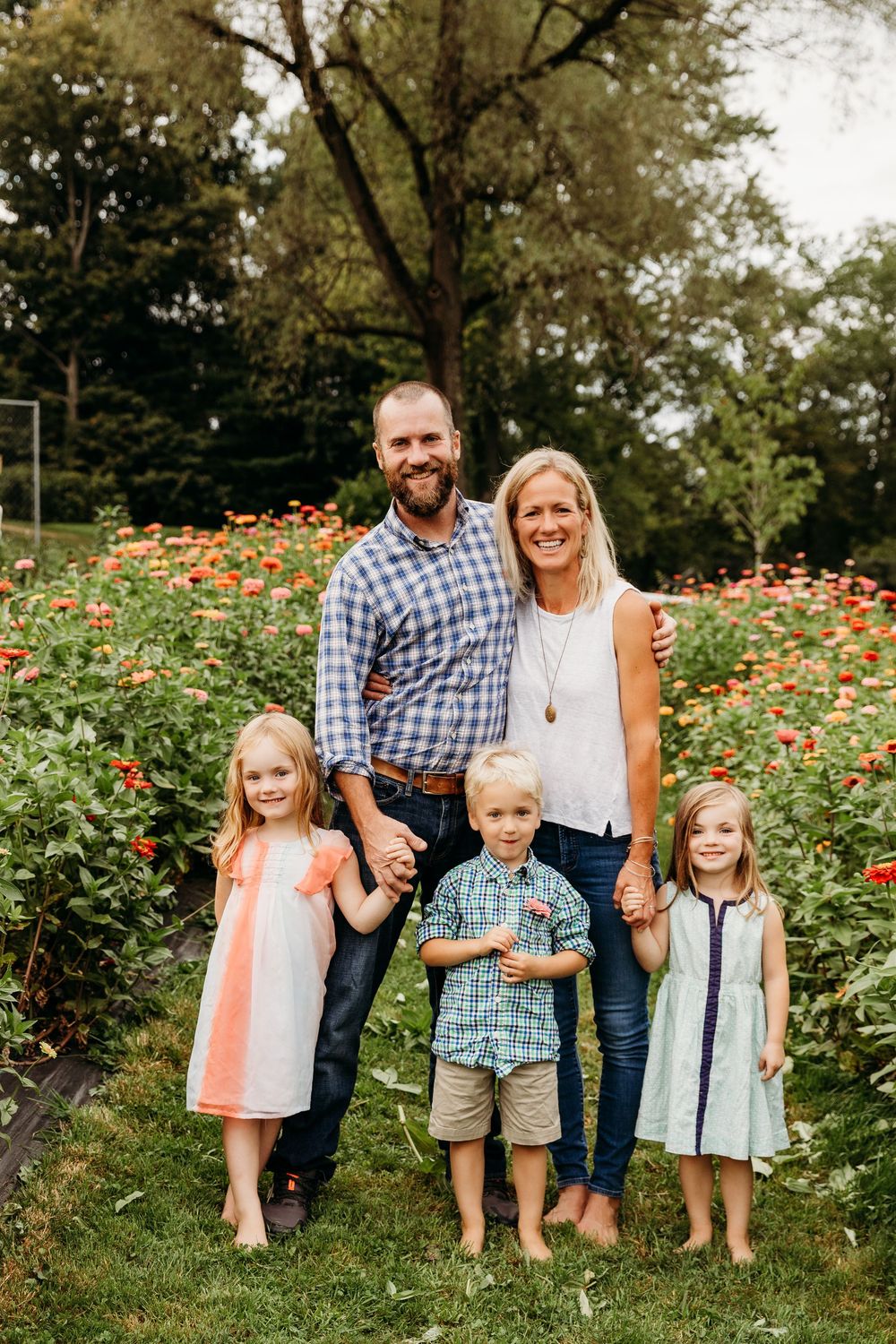 Happy family poses together in a blooming flower garden during golden hour.