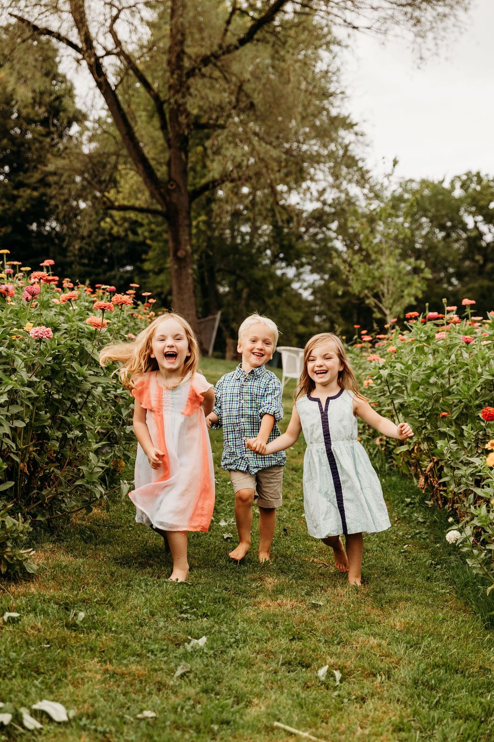 Children running and jumping with excitement through a garden path surrounded by flowers.