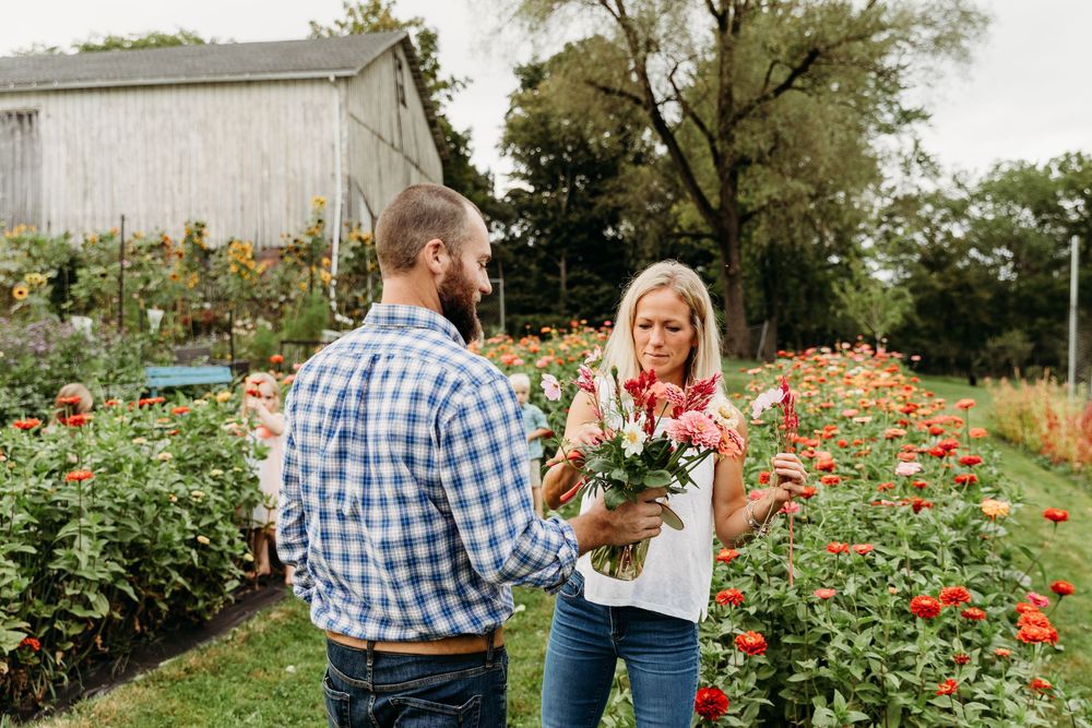 Family spending time together in a garden filled with red and orange flowers.