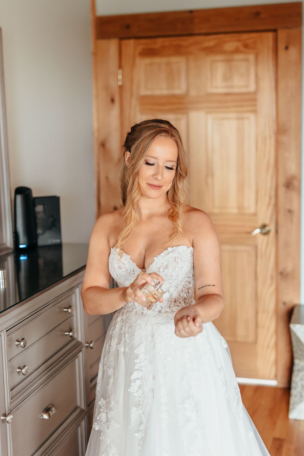 A white lace wedding dress hanging in a room with warm wood paneling.