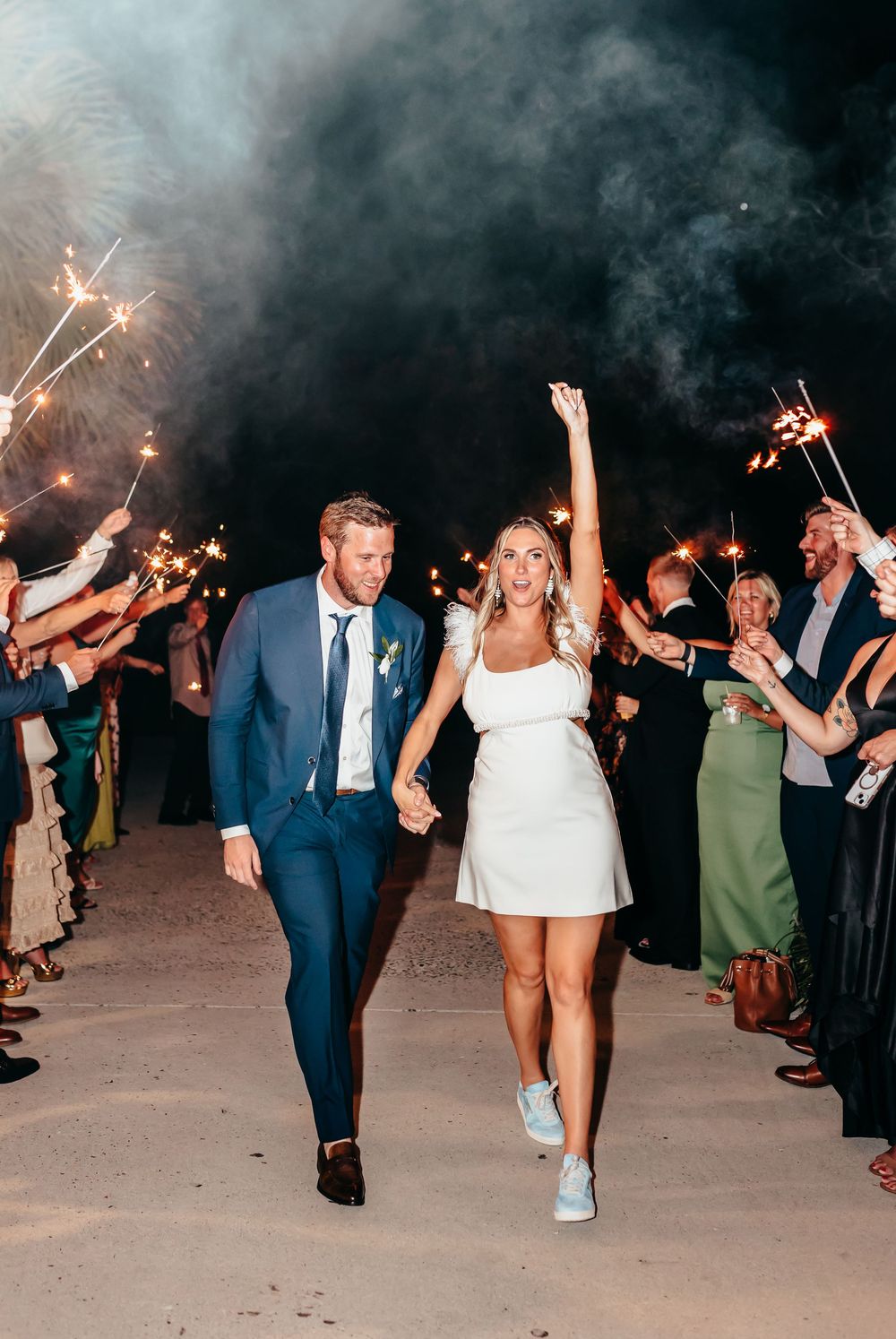 Wedding party guests dancing and celebrating with sparklers during a nighttime reception.