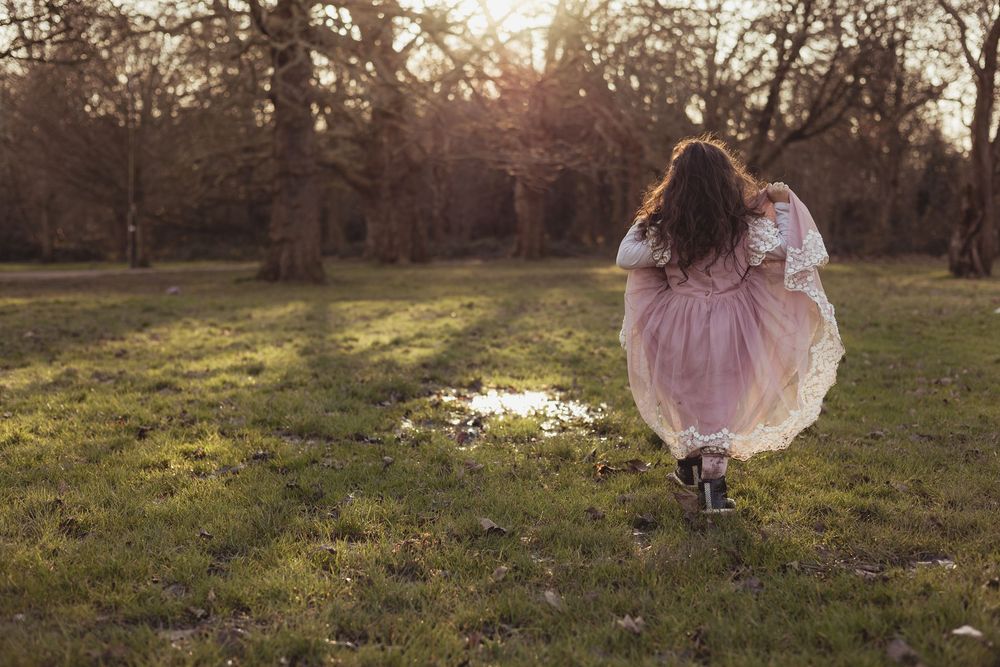 girl in pink dress outdoors at sunset in the woods