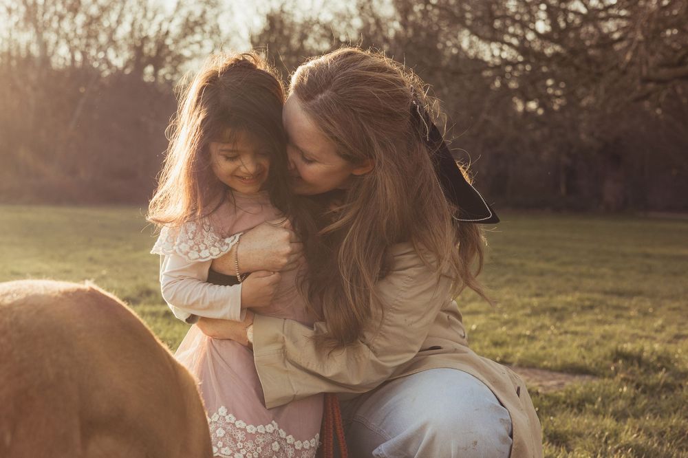 mum and daughter hugs outside at sunset