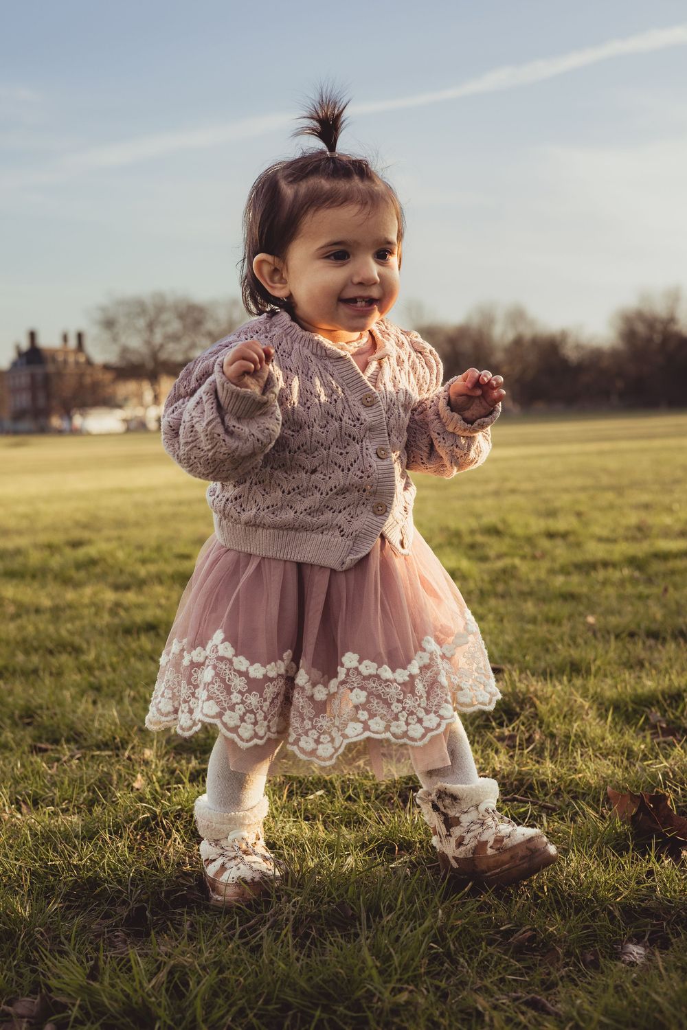 baby girl walking in pink dress outdoors