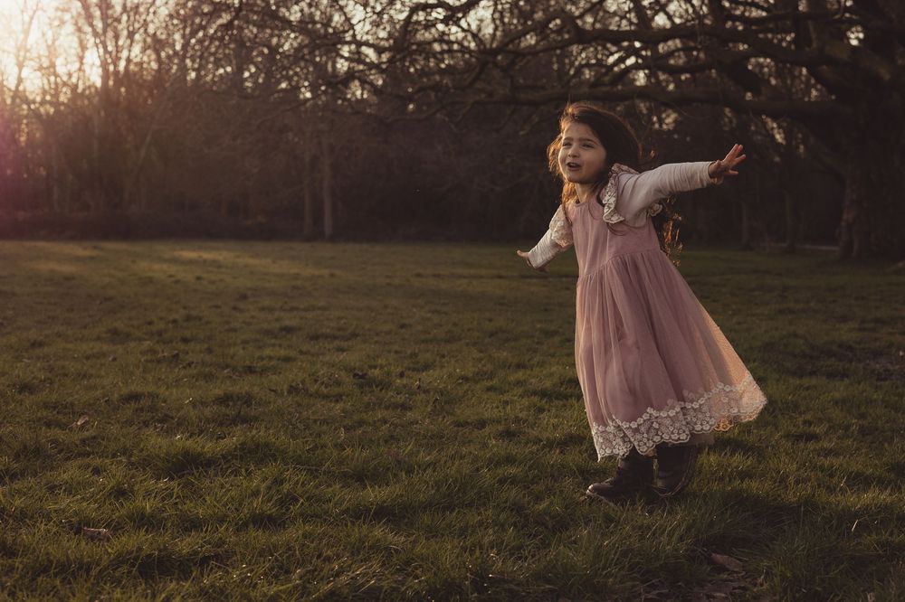 girl spins around in pink dress on Wandsworth common at sunset