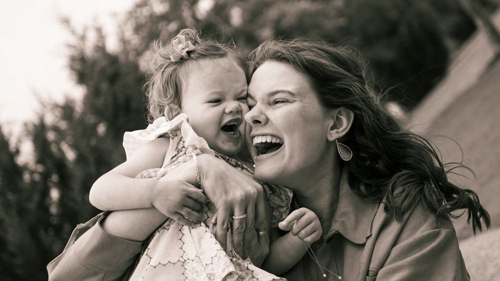 A joyful candid moment captured in black and white showing pure emotional connection and laughter outdoors.