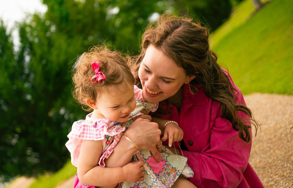 A tender moment shared between parent and child outdoors in a green garden setting with warm sunlight.
