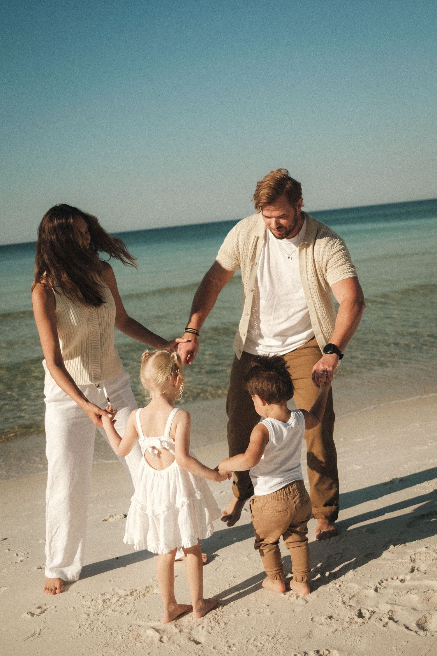 Family walking and playing together along a pristine beach shoreline.