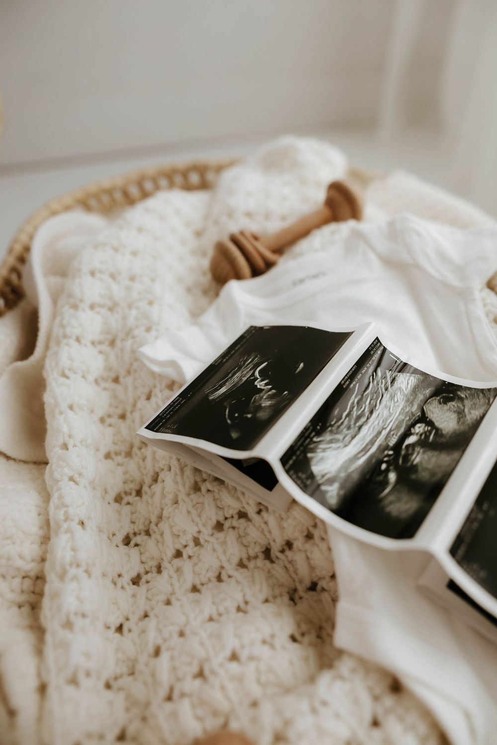 Ultrasound photos rest on a cozy white knitted blanket in a wicker basket.