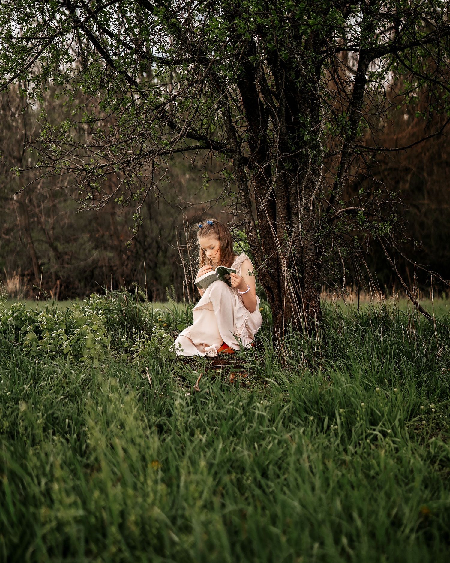 A twirling figure in a vintage-style cream dress and brown boots stands in a green field under cloudy skies.